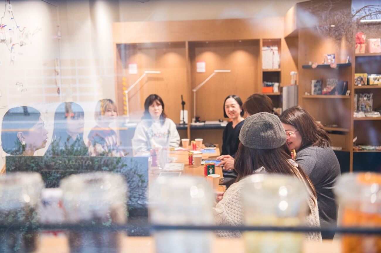 写真：イベントにて参加者がテーブルを囲み、笑いを交えながら話し合う様子