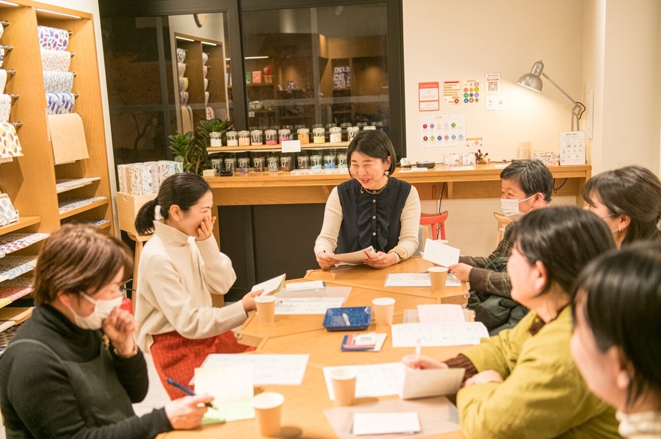 写真：イベントにて参加者がテーブルを囲み、笑いを交えながら話し合う様子