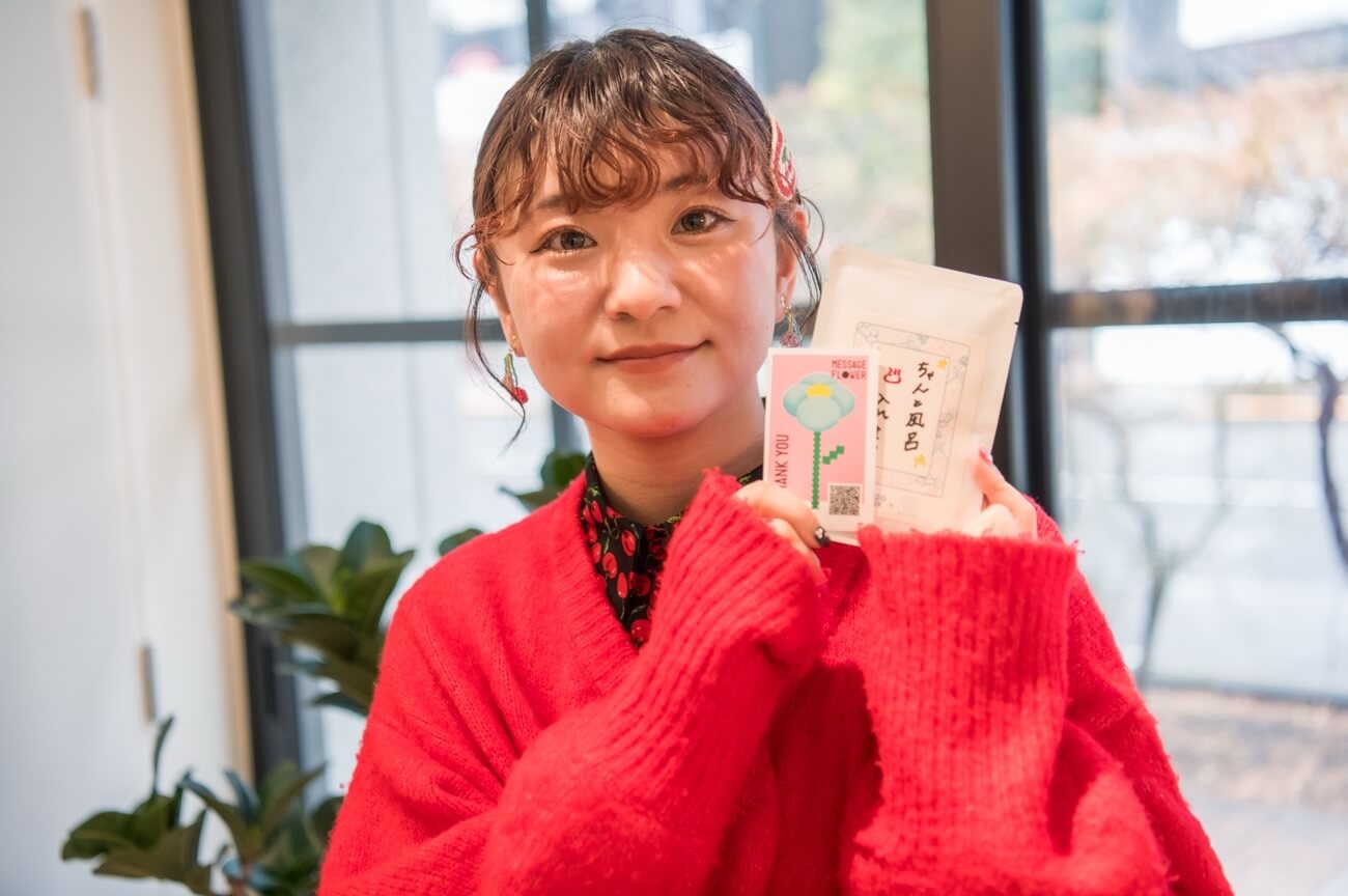 写真：完成した入浴剤とメッセージカードを手に笑顔を見せるま ち こさん